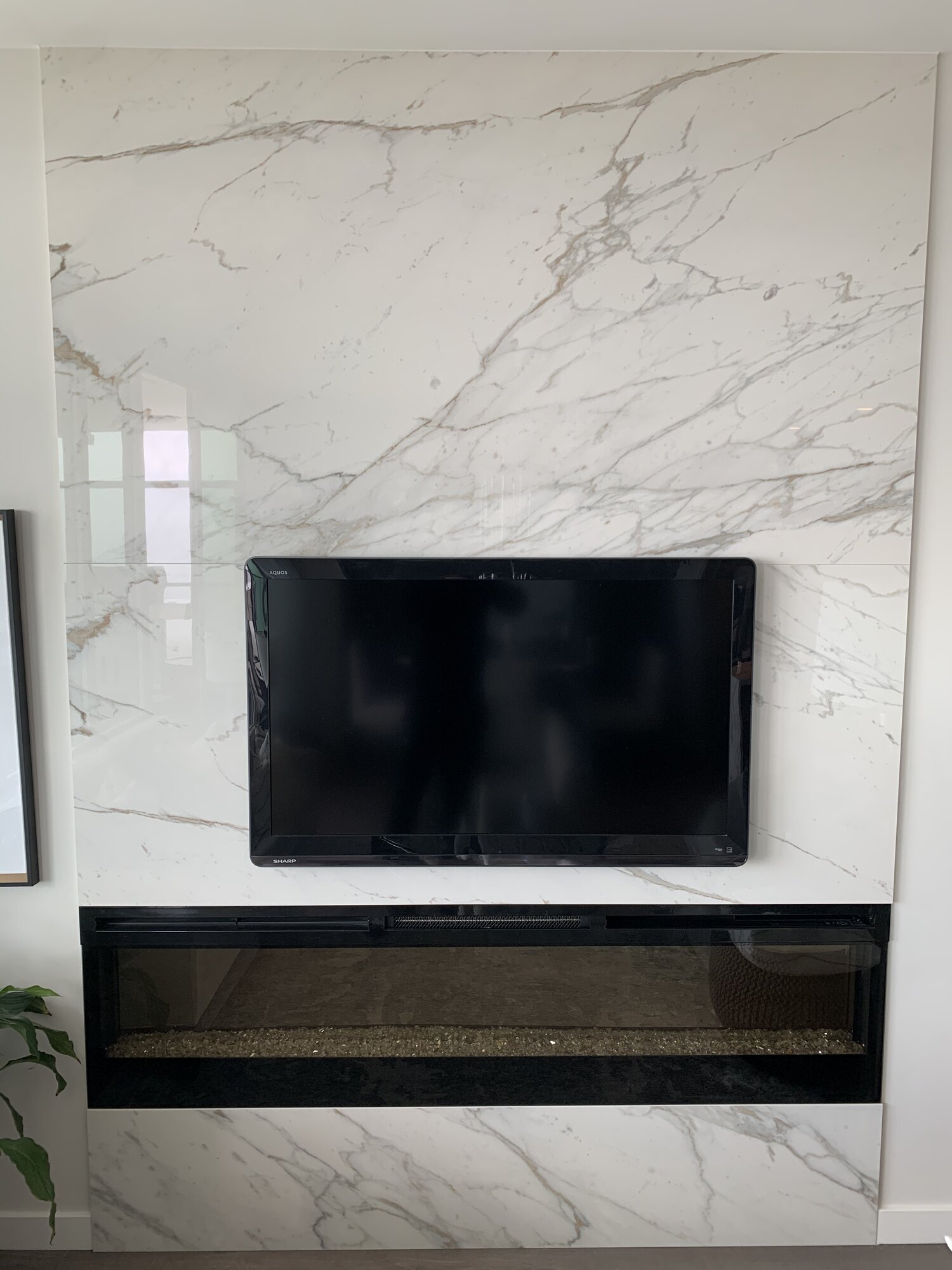Full-height book-matched Calacatta porcelain slab fireplace wall with a linear gas insert