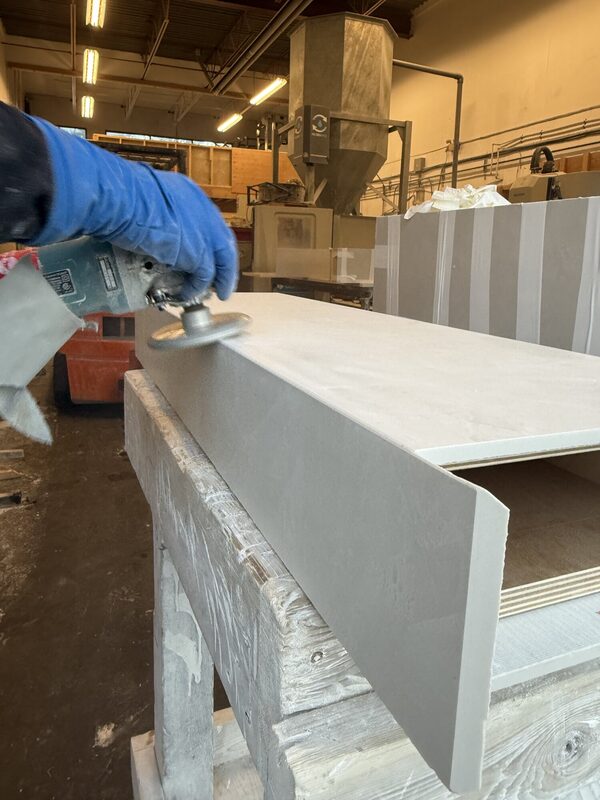 Gloved hand polishing the mitred edge of a large-format porcelain stair tread