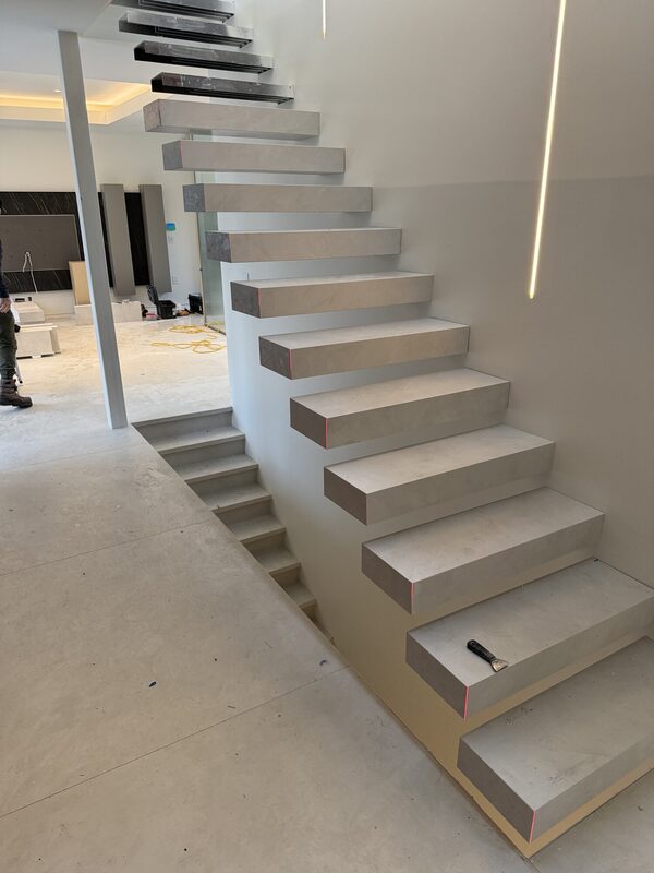 Custom-fabricated porcelain-clad floating treads with mitred edges, glass railing and concealed cove lighting.