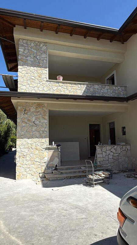 Villa facade with hand-cut irregular natural stone cladding and deep timber eaves