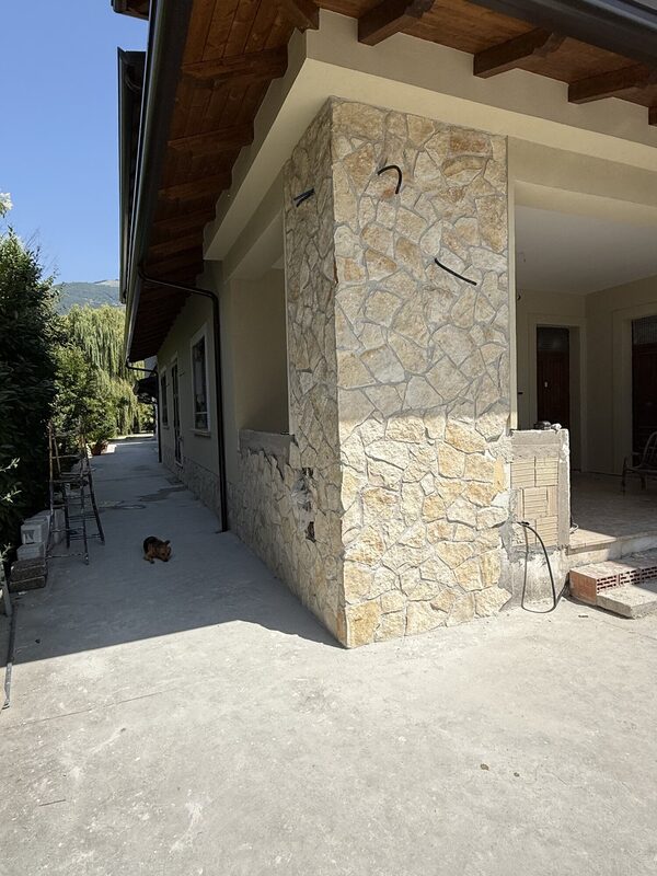 Full-height entry column clad in cleft-face natural stone with tight dry-look joints