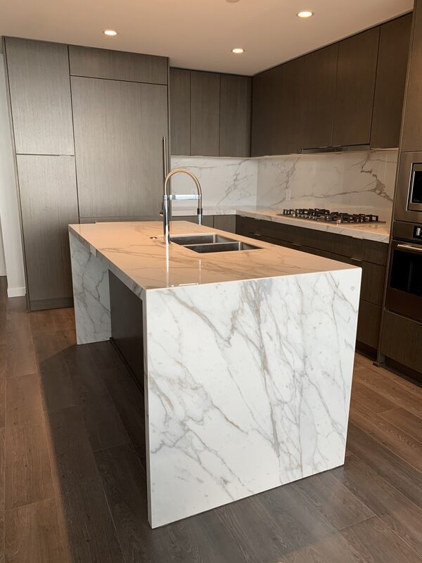 Kitchen counters, waterfall islands and full-height slab backsplashes in porcelain and quartz.