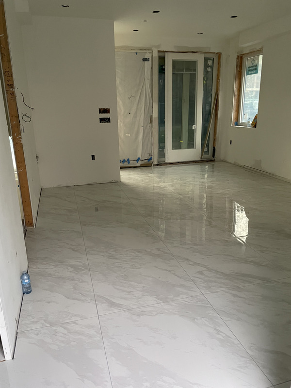 Polished marble-look large-format porcelain floor run wall to wall with minimal grout lines and level, lippage-free joints.