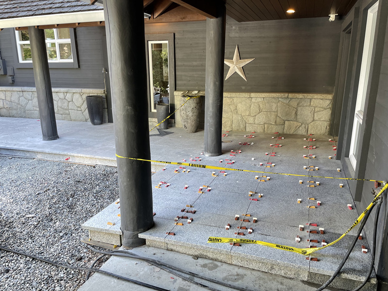 Exterior porcelain pavers being set on a covered terrace with leveling clips and wedges holding each slab flat during installation