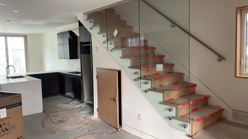 Timber-clad stair with frameless glass balustrade and stainless handrail.