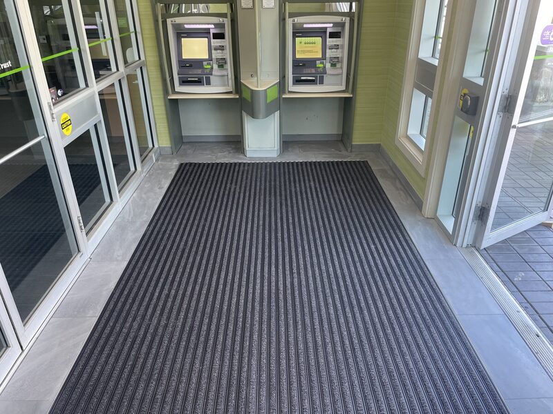 Commercial entrance replacement — worn carpet removed and rebuilt with a heavy-duty recessed entry mat and tile surround.