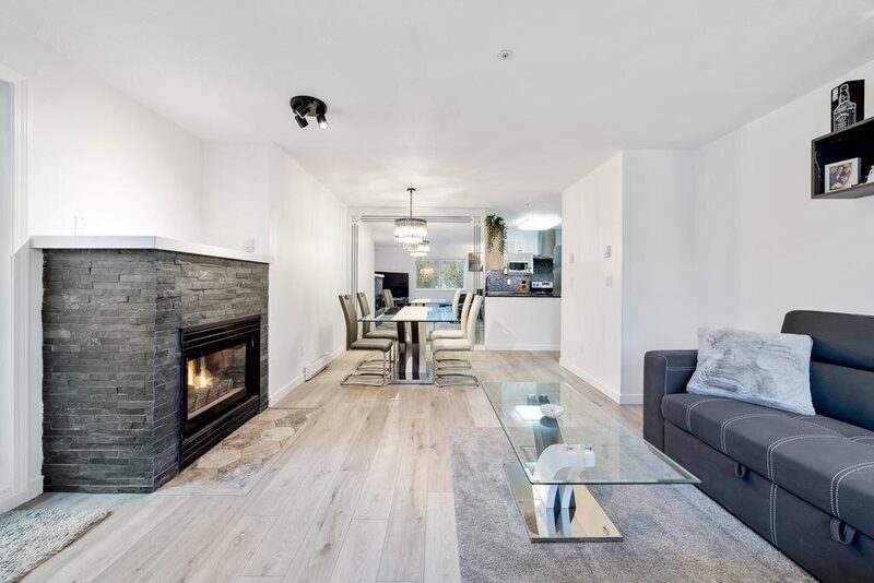 Stacked stone fireplace surround with the firebox lit and timber mantel above