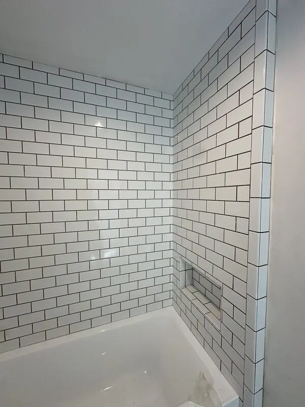 White subway tile shower with contrasting dark grout and a flush recessed niche