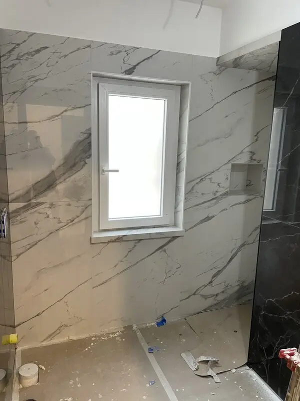 White Calacatta-look and black marble-look porcelain slabs meeting at a shower corner