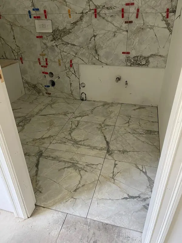 Book-matched Calacatta-look porcelain slab shower walls with matching floor