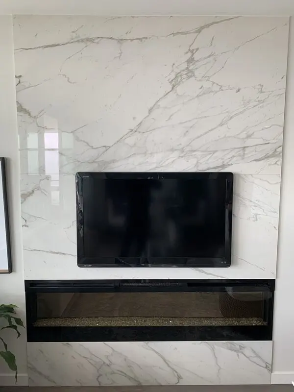 Full-height book-matched Calacatta porcelain slab fireplace wall with a linear gas insert
