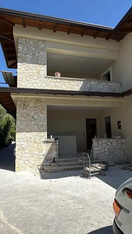Villa facade with hand-cut irregular natural stone cladding and deep timber eaves