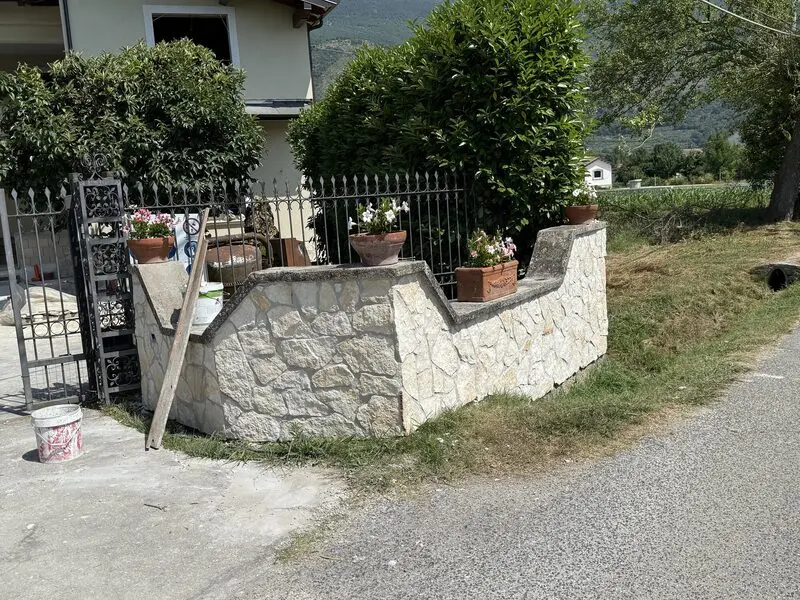 Random-coursed natural stone garden wall capped in stone beside an iron gate