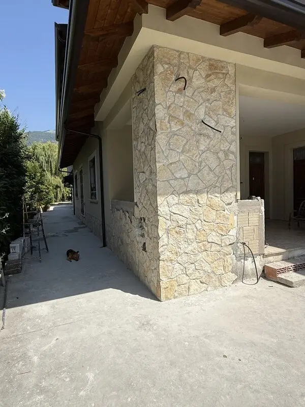 Full-height entry column clad in cleft-face natural stone with tight dry-look joints