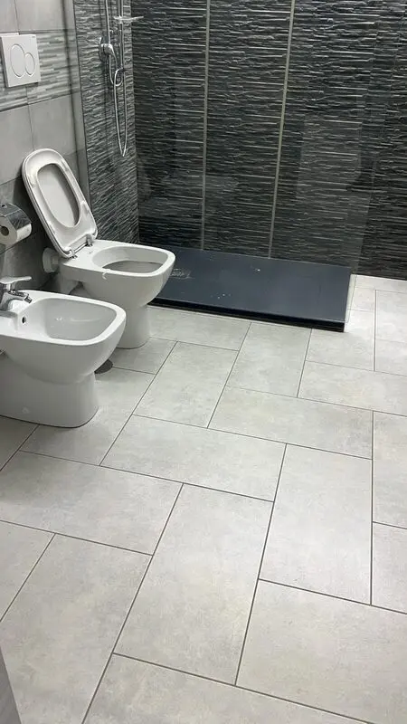 Bathroom with ribbed dark porcelain feature wall and pale stone-look floor tile