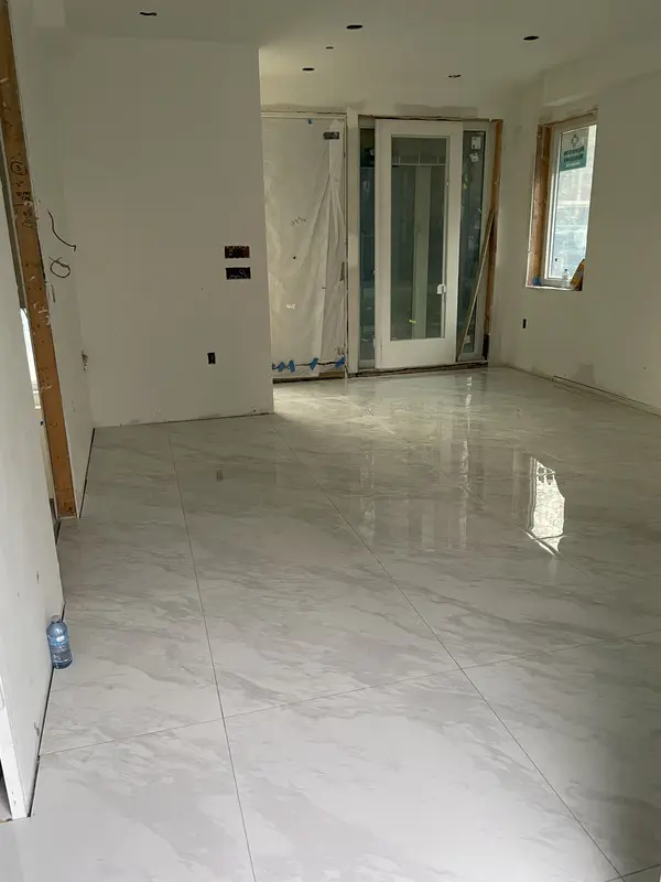 Polished marble-look large-format porcelain floor run wall to wall with minimal grout lines and level, lippage-free joints.