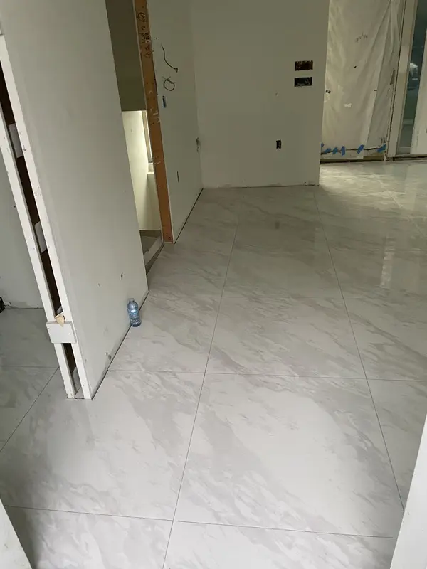 Marble-look porcelain floor continuing through a hallway threshold with grout lines aligned across rooms