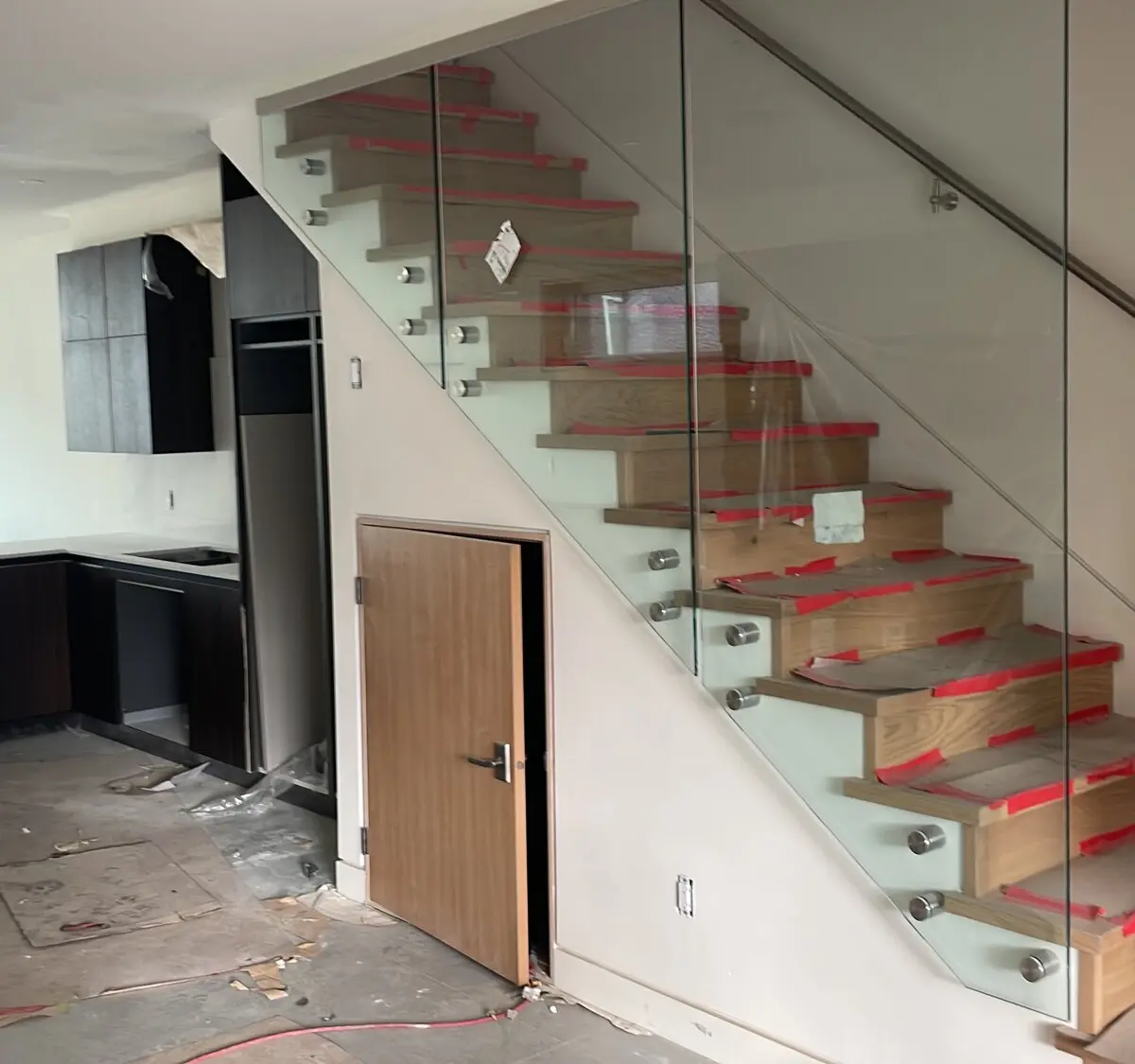 Oak-clad stair treads with frameless glass balustrade and slim stainless handrail