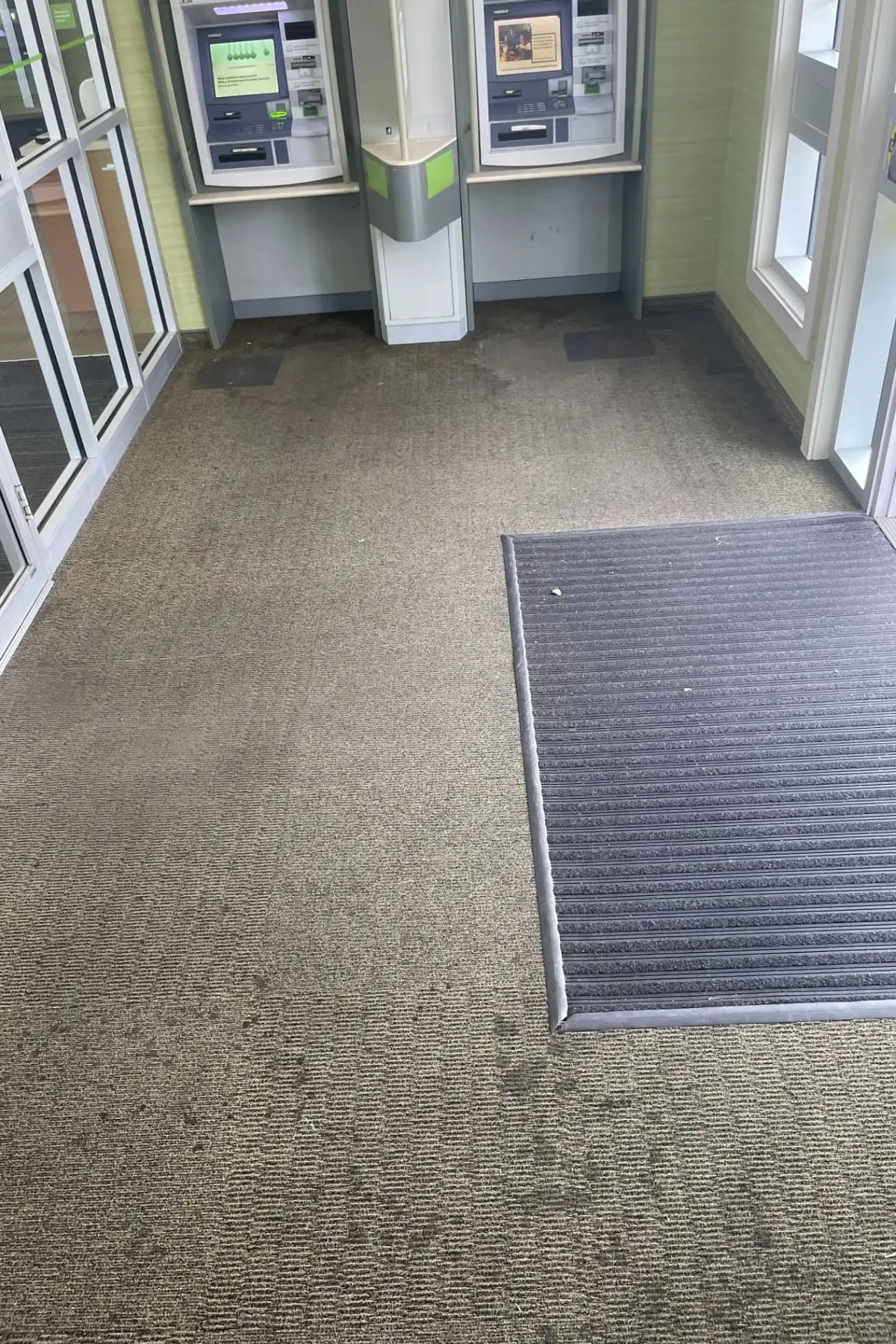 TD bank entrance vestibule with worn carpet and a loose mat before renovation