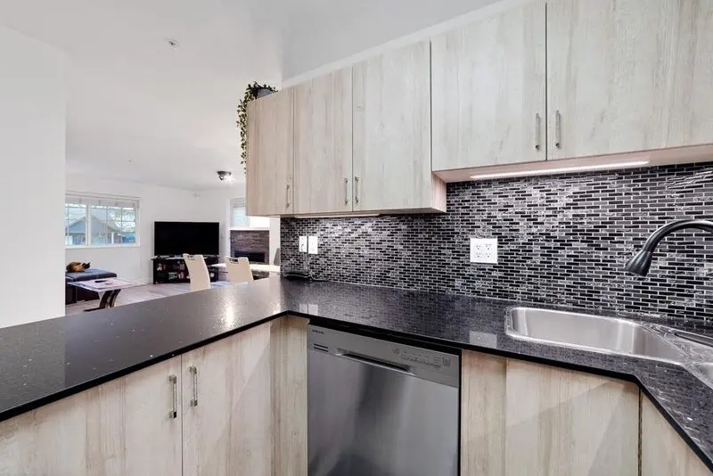Kitchen with speckled granite counters and an iridescent glass mosaic backsplash