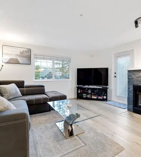 Living room with a floor-to-ceiling stacked stone fireplace wall and hardwood flooring