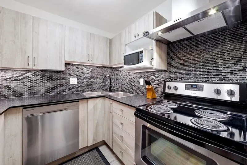 Granite peninsula counter with mosaic backsplash and stainless appliances