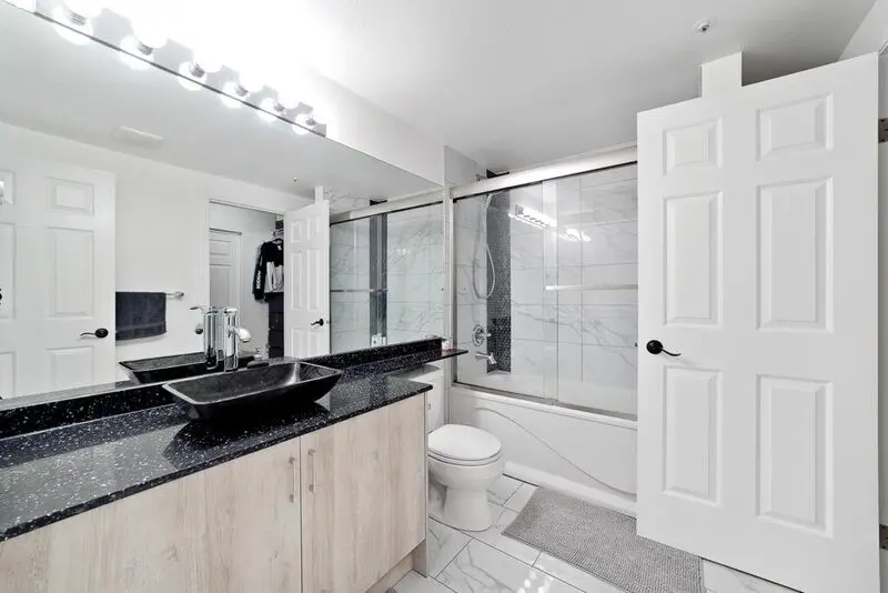 Renovated bathroom with a granite vanity top and tiled tub surround