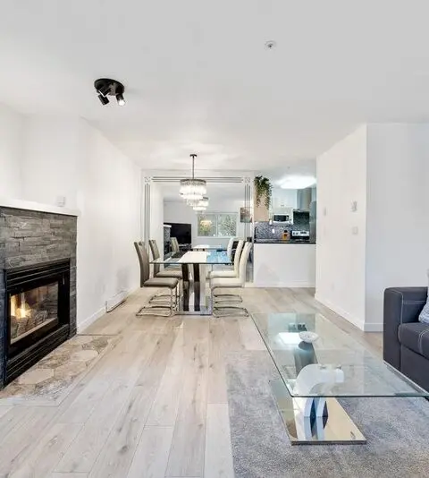 Stacked stone fireplace surround with the firebox lit and timber mantel above